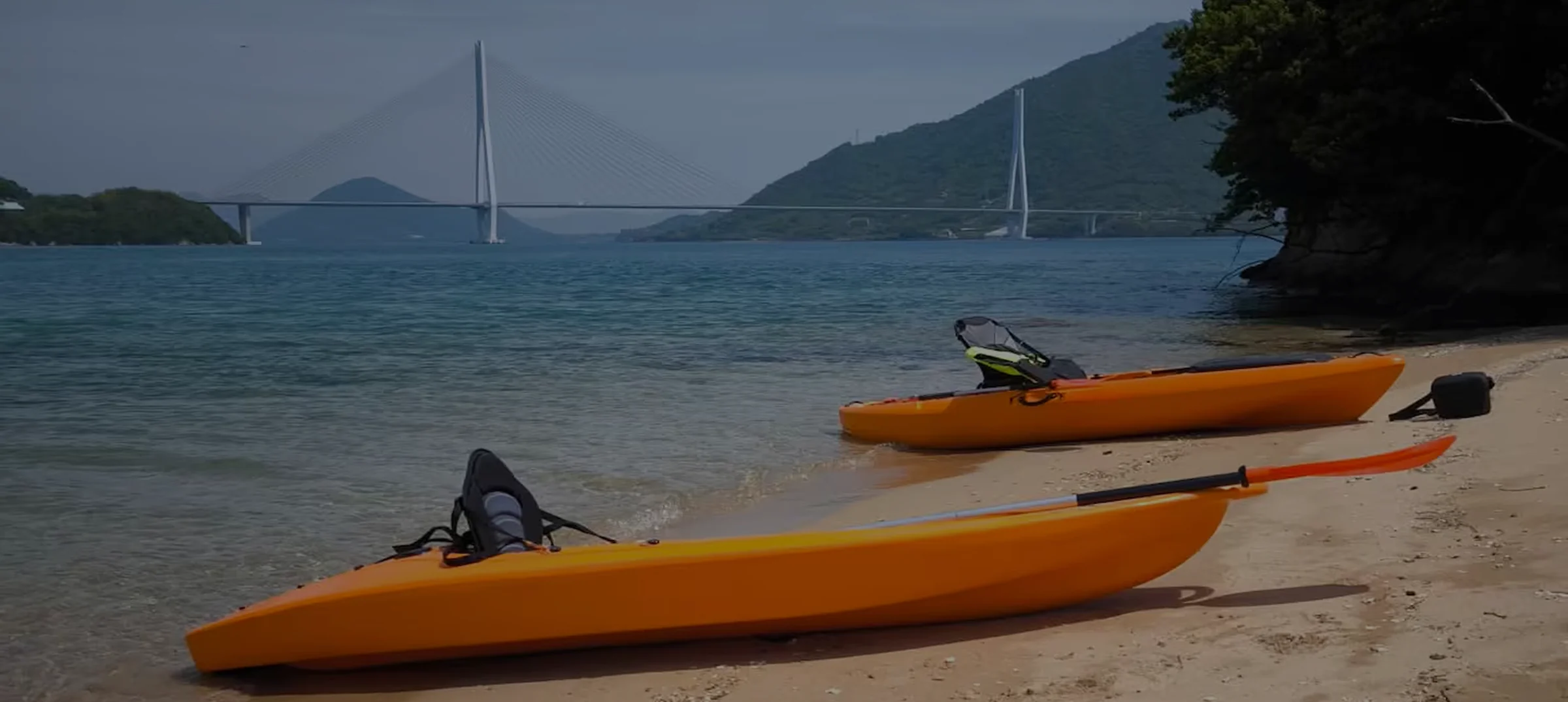 Kayaks on a sandy beach with the Tatara Bridge across the Seto Inland Sea