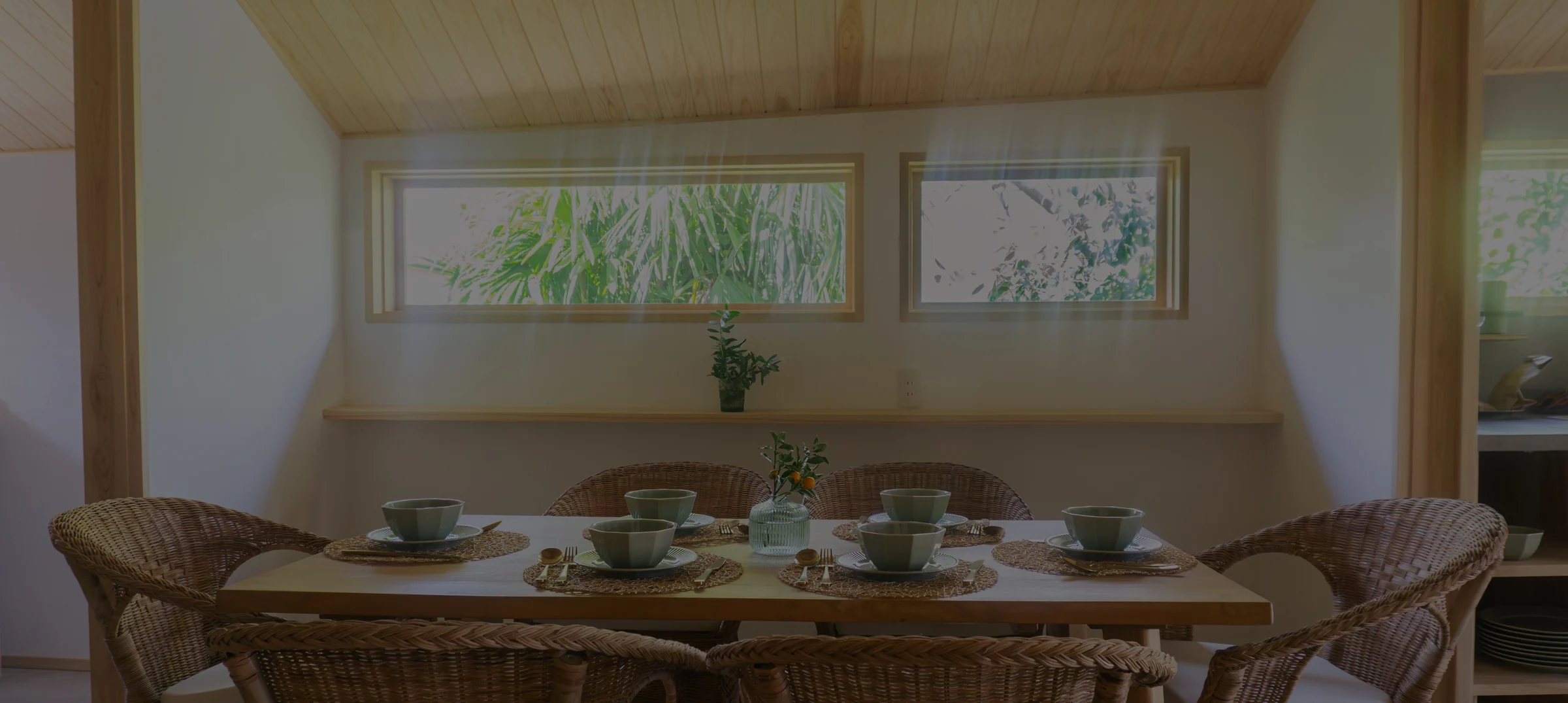 The restored dining room, wicker chairs drawn around a timber table beneath a cedar ceiling